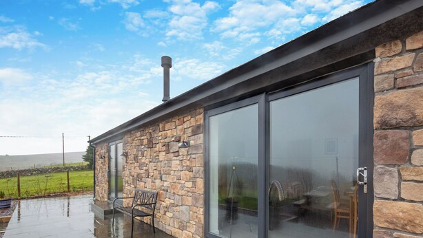 Un bâtiment en pierre avec une porte en verre et un banc à l’extérieur.