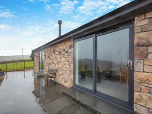 A stone building with a glass door and a bench outside.