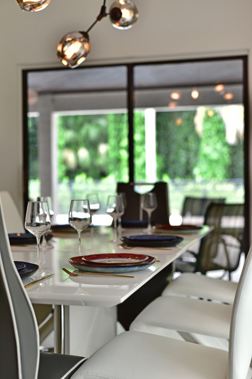A dining area with a long table, chairs, and a view of greenery outside.