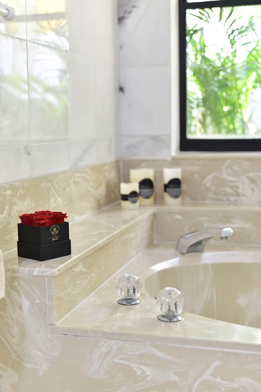 Un baño con encimera de mármol, un lavamanos con grifo moderno y una ventana con vistas al verdor.