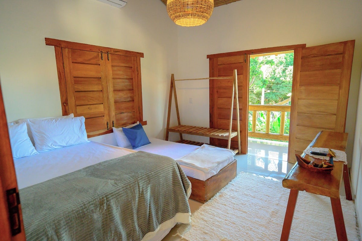 A room with two beds, a wooden bench, and a small table with a remote control.