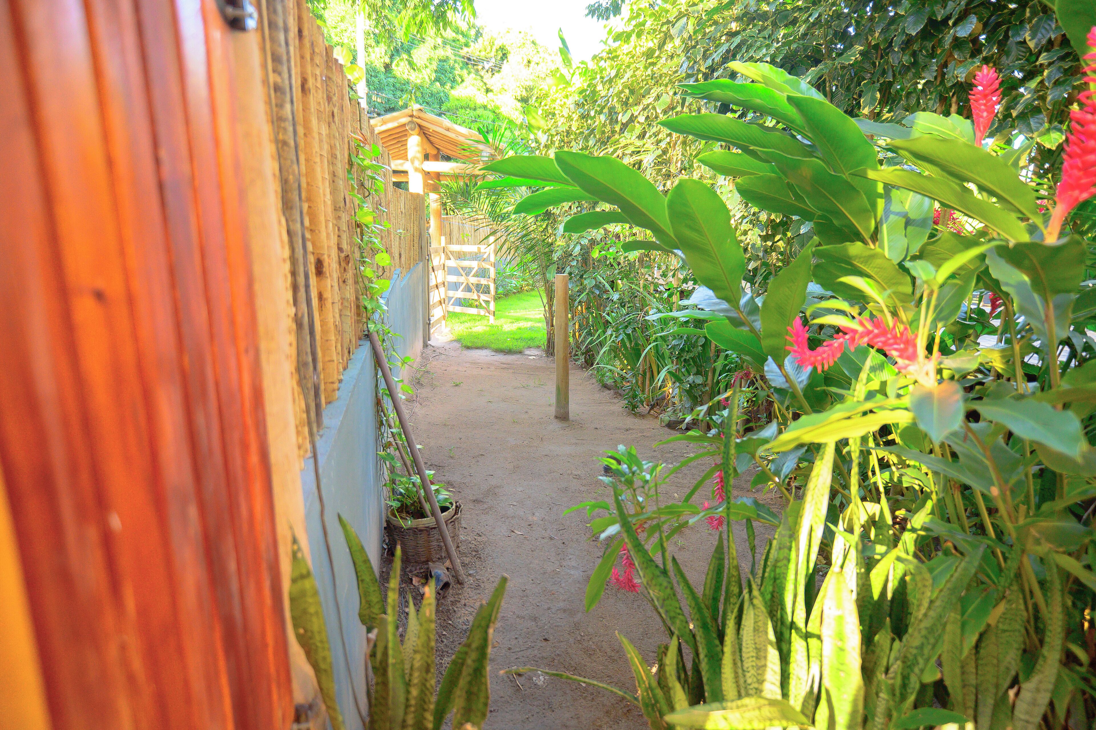 A garden pathway leading to a wooden structure with a thatched roof.