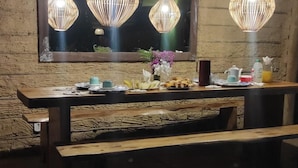 A wooden table set with plates, cups, and a vase of flowers, with wicker lamps above. - Villa Beija Flôr (Porto Seguro)