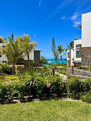A resort with a pool, palm trees, and a view of the ocean.