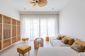 A modern living room with a sofa, ottoman, coffee table, and a wooden partition.