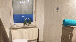 A bathroom with a toilet, a radiator, a window with a view, and a towel rack. - Appartement für 2 Personen in Ruhiger Lage (Ilsede)
