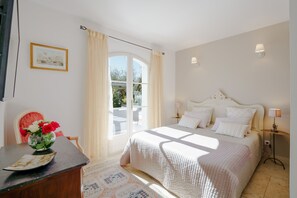 Cozy retreat with a large bed, nightstand, and comfortable chair, featuring a beautiful view through the large window.