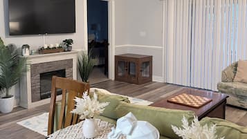 A living room with a flat-screen TV, a fireplace, a ceiling fan, a coffee table, and a sofa.