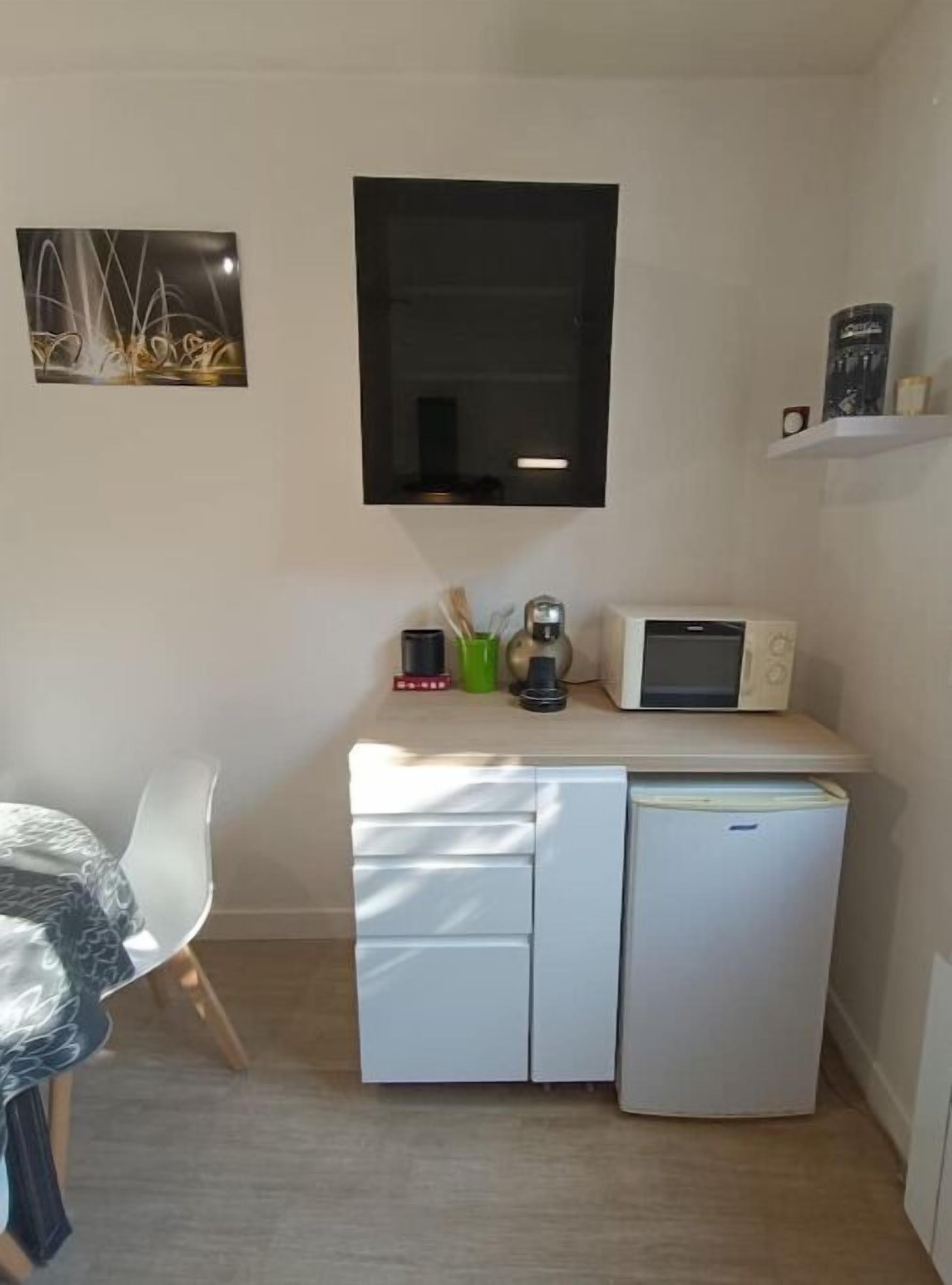 Une petite cuisine équipée comprenant un four à micro-ondes, un petit réfrigérateur et une machine à café, le tout installé sur un plan de travail.