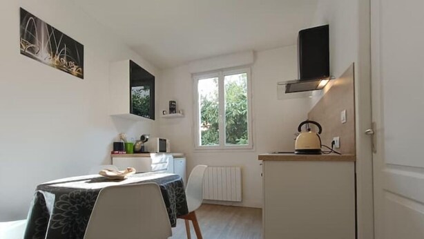 Une cuisine compacte avec un coin repas, une fenêtre donnant sur un espace verdoyant et une cuisinière intégrée.