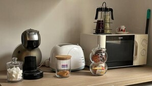 Un plan de travail de cuisine avec une machine à café, un grille-pain, un four à micro-ondes et des bocaux de café et de sucre.