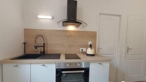 Une cuisine compacte équipée d’un évier, d’une cuisinière et d’une bouilloire.
