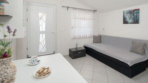 A minimalist bedroom with a bed, a bedside table, a white door, and a window with curtains. - Nice apartment for 4 people with WIFI, A/C, TV and terrace (Biograd Na Moru)