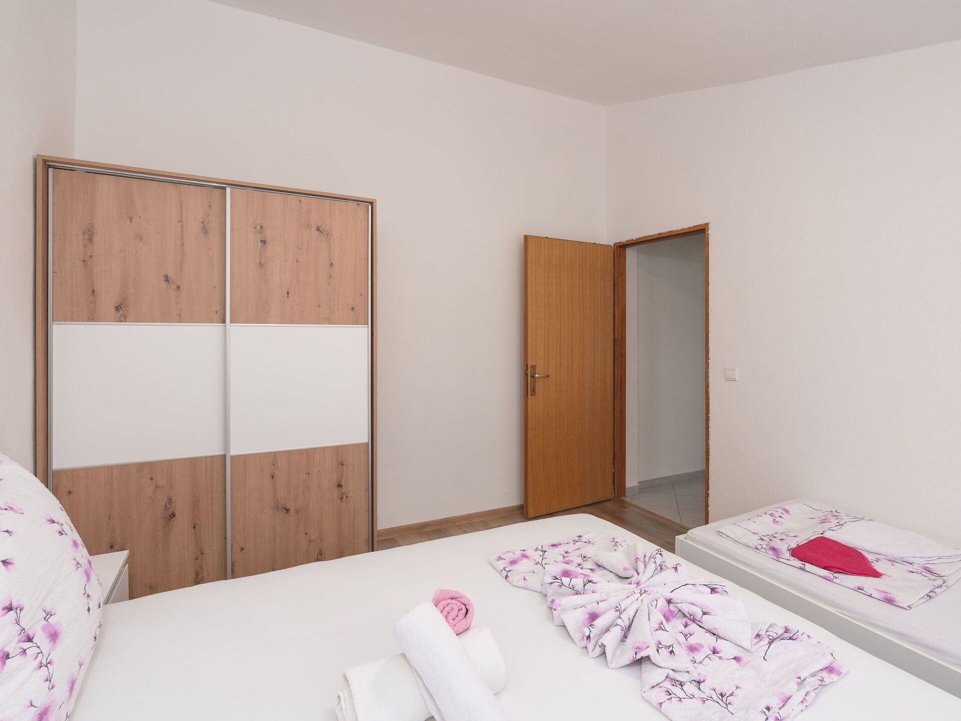 Ein Schlafzimmer mit einem Holfischschrank, einem Einzelbett mit floralem Bettbezug und einem Nachttisch.