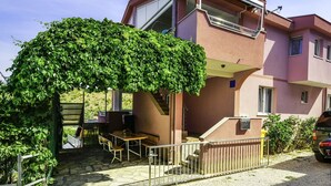 A two-story residential building with a covered patio area, outdoor seating, and a car parked nearby. - Nice apartment for 4 people with WIFI, A/C, TV and terrace (Biograd Na Moru)
