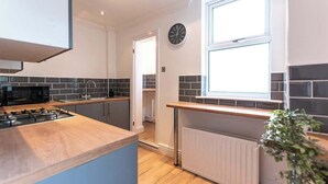A modern kitchen with a wooden countertop, black microwave, and a clock on the wall. - Stylish Flat, Ideal for Business & Long-Term Stays (Liverpool)