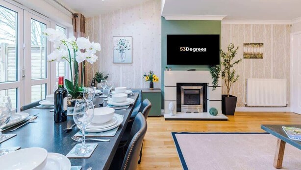 Ein modernes Wohnzimmer mit Essbereich, Kamin und Wand-Fernseher.