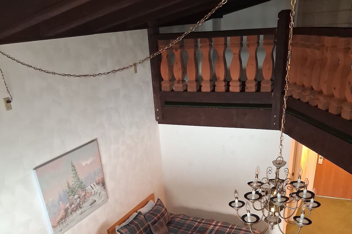 A cozy room with two beds, a painting on the wall, and a chandelier.