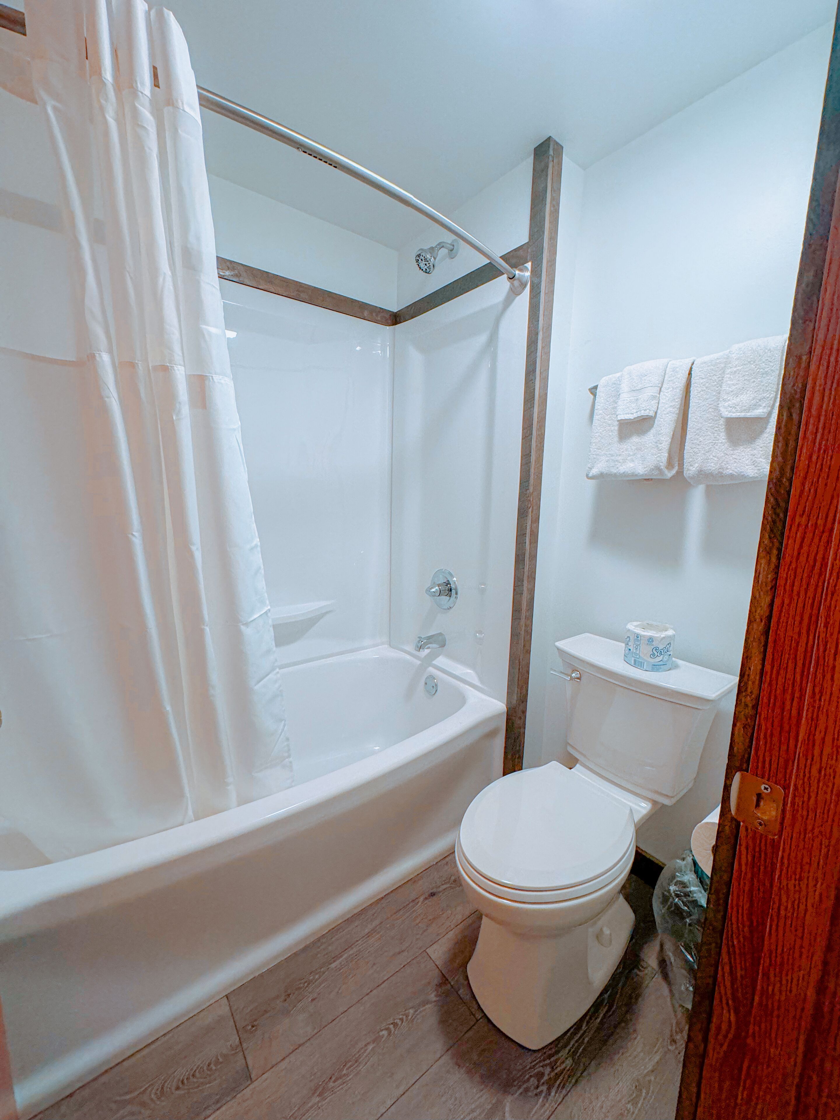 A bathroom with a bathtub, toilet, and shower curtain.