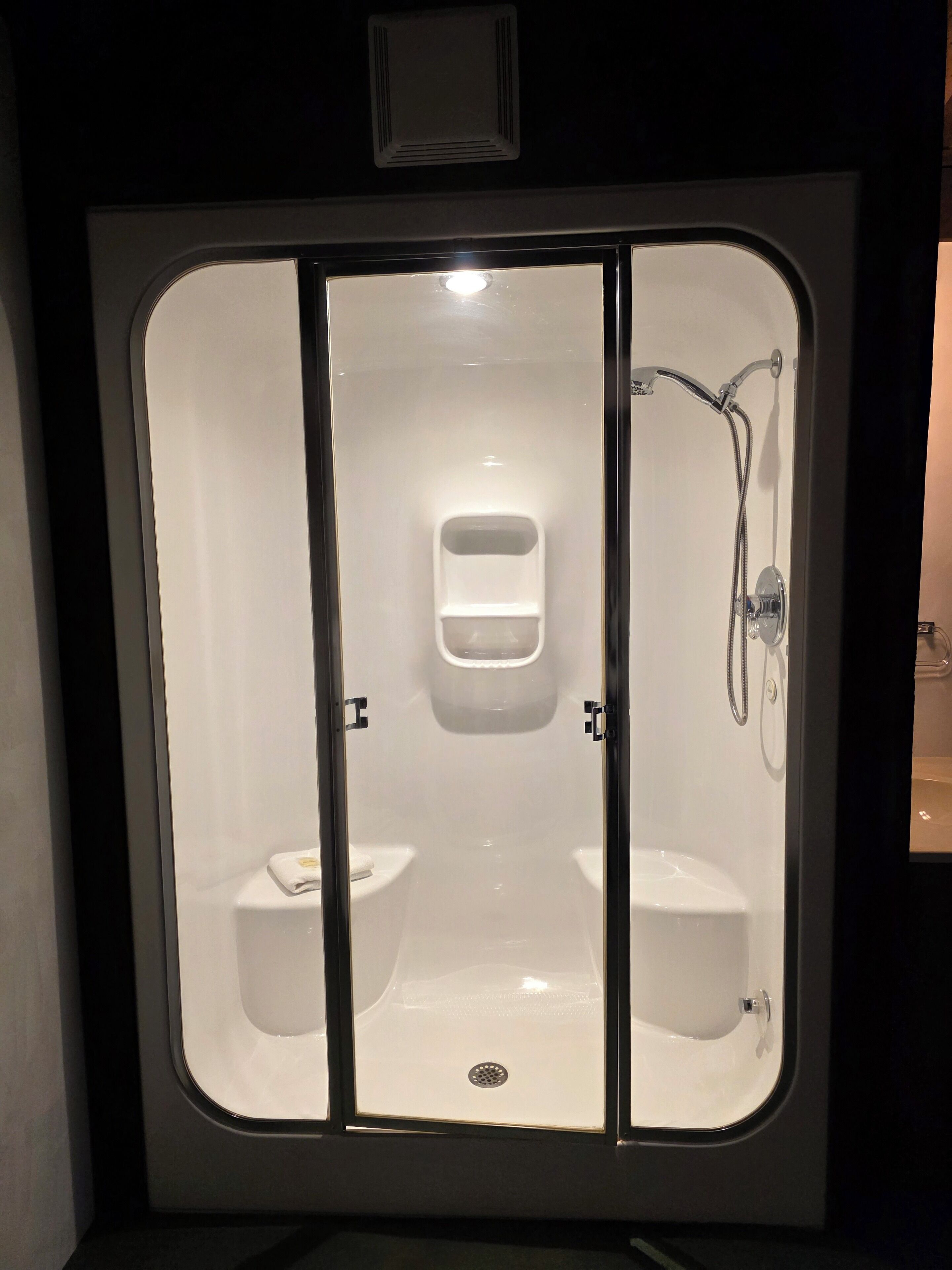A bathroom with a shower, two sinks, and a toilet.
