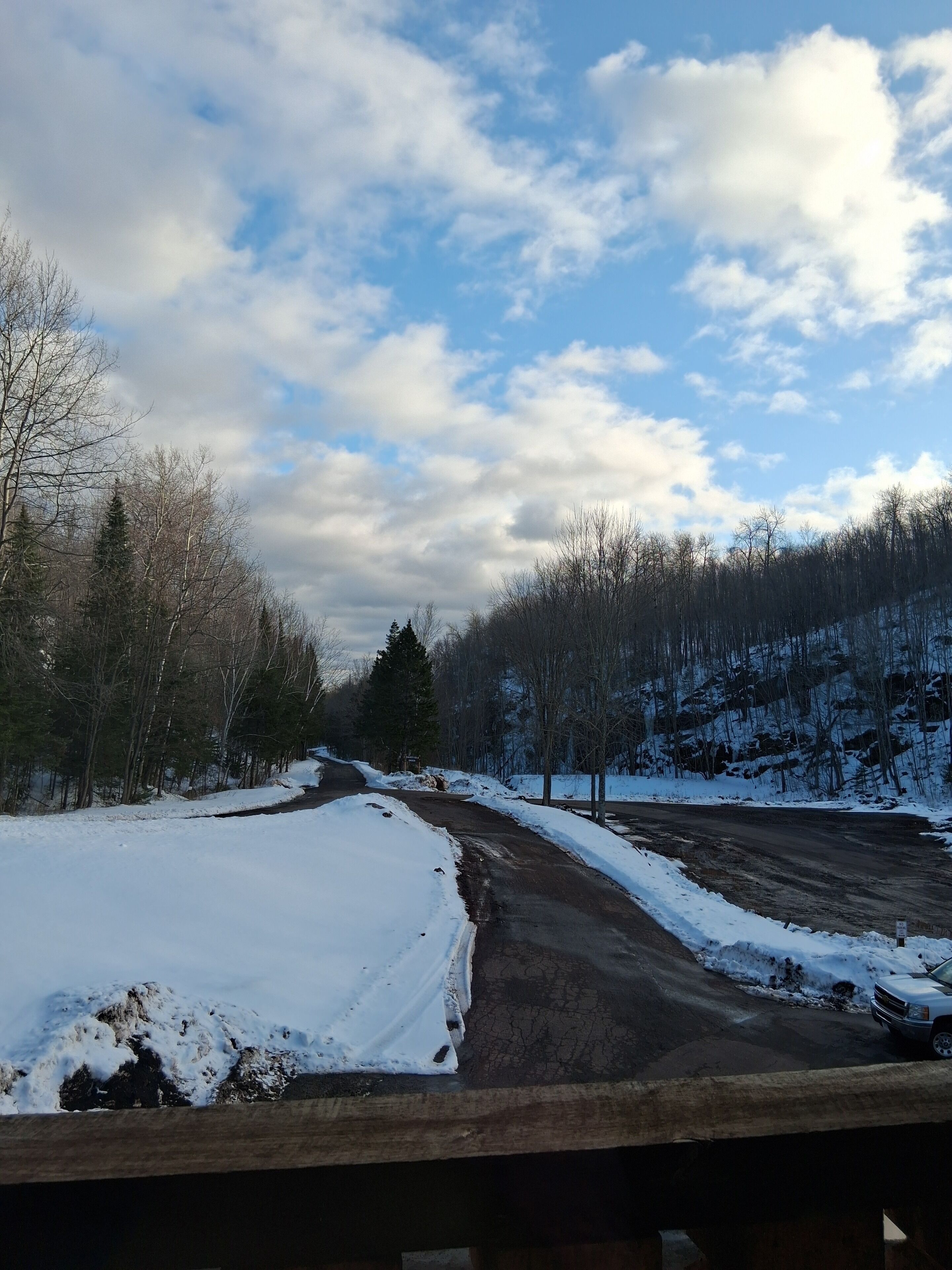 Carretera coberta de neu amb un pont de fusta al primer pla.