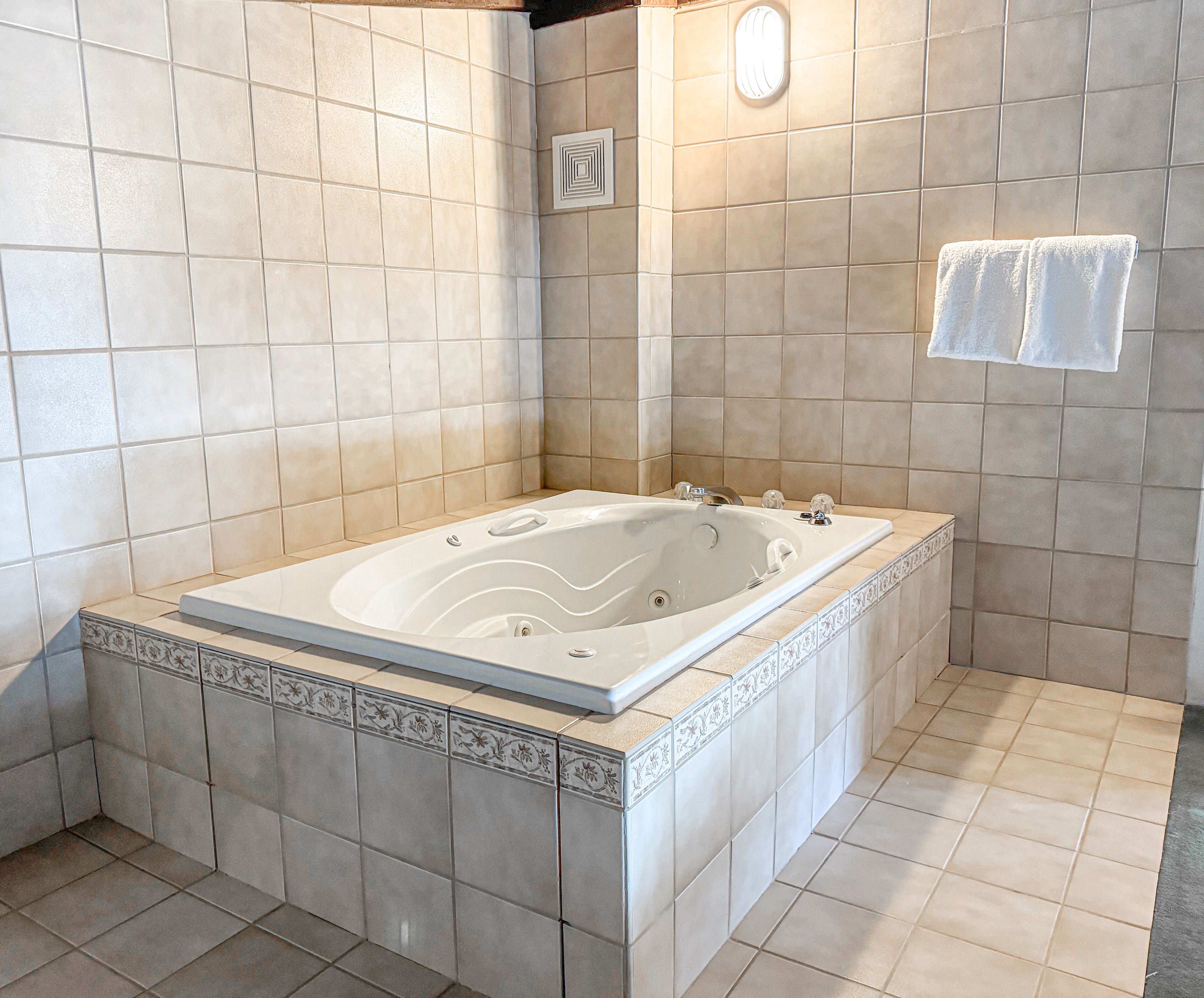 Une salle de bain avec une grande baignoire, des murs carrelés et un espace douche.
