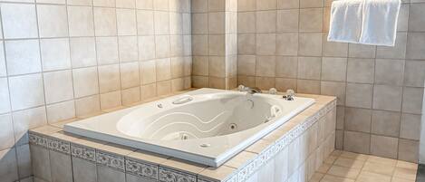 Une salle de bain avec une grande baignoire, des murs carrelés et un espace douche.