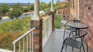 Un balcon avec deux chaises et une table, donnant sur une rivière et un paysage verdoyant.