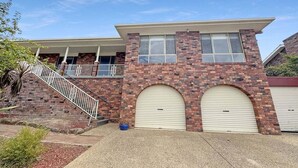 Un bâtiment à deux étages avec une façade en briques, un porche couvert et deux portes de garage.