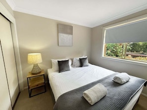 Une chambre d’hôtel avec un lit, une lampe de chevet, une fenêtre donnant sur un beau paysage et un tableau accroché au mur.