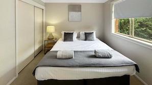 Une chambre à coucher avec un lit, des lampes de chevet, une fenêtre et une porte.
