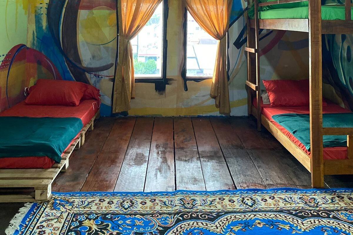 A room with bunk beds, a colorful mural, and a patterned rug.