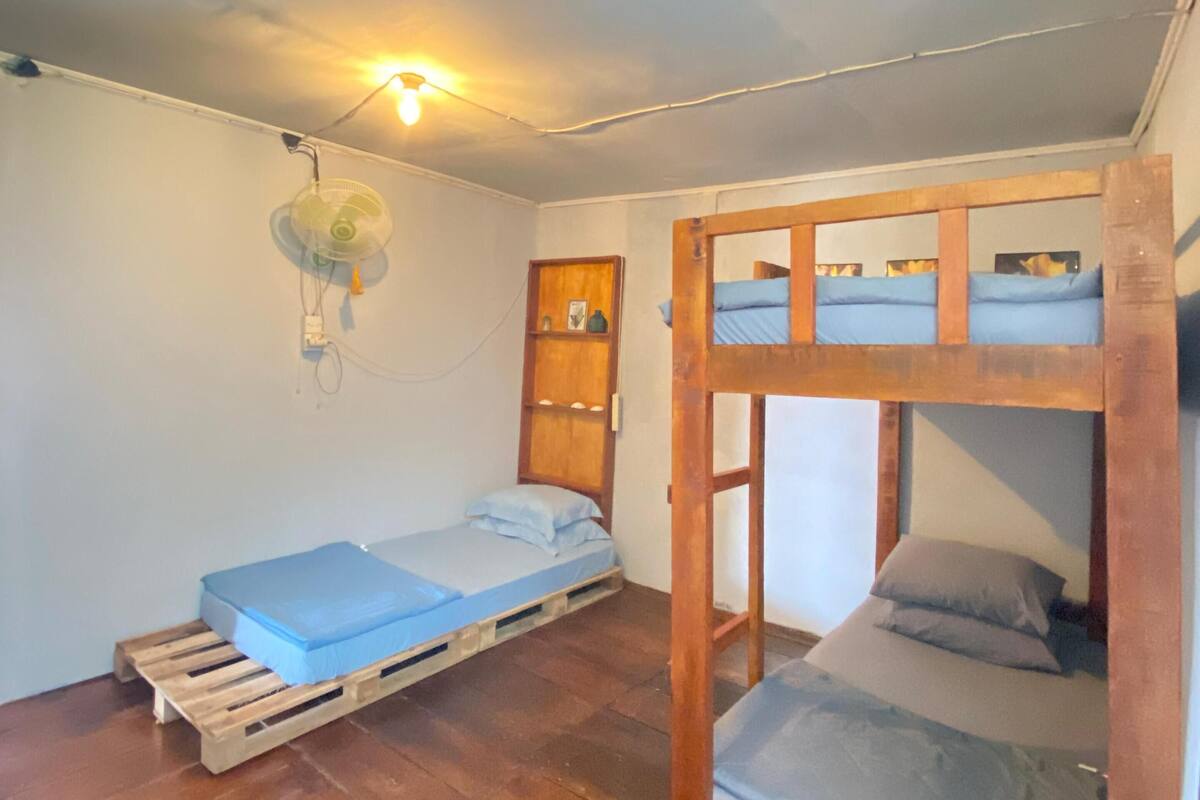 A dormitory-style room with two bunk beds and a single bed on a wooden pallet.