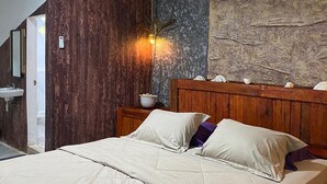 A bedroom with a bed, wooden headboard, wall-mounted air conditioner, and a nightstand with a bowl. - Second Hope Lodge (Padang)