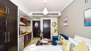 Ein Hotelzimmer mit Bett, Sofa, Esstisch, Küchenzeile und Bad.