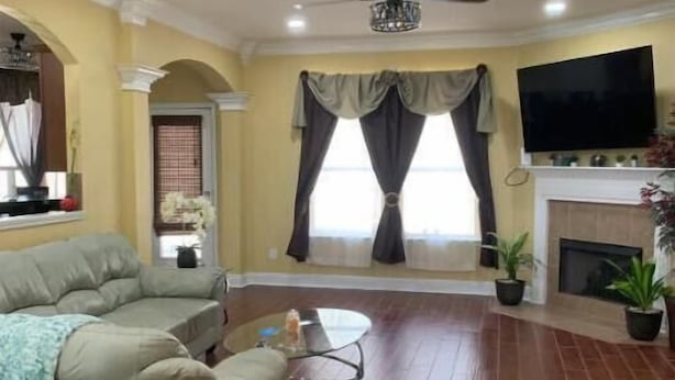 Una sala de estar con sofá, televisión, chimenea y ventilador de techo.