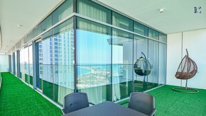Un espace de bureau moderne avec des murs en verre, une vue sur le paysage urbain et un fauteuil suspendu.