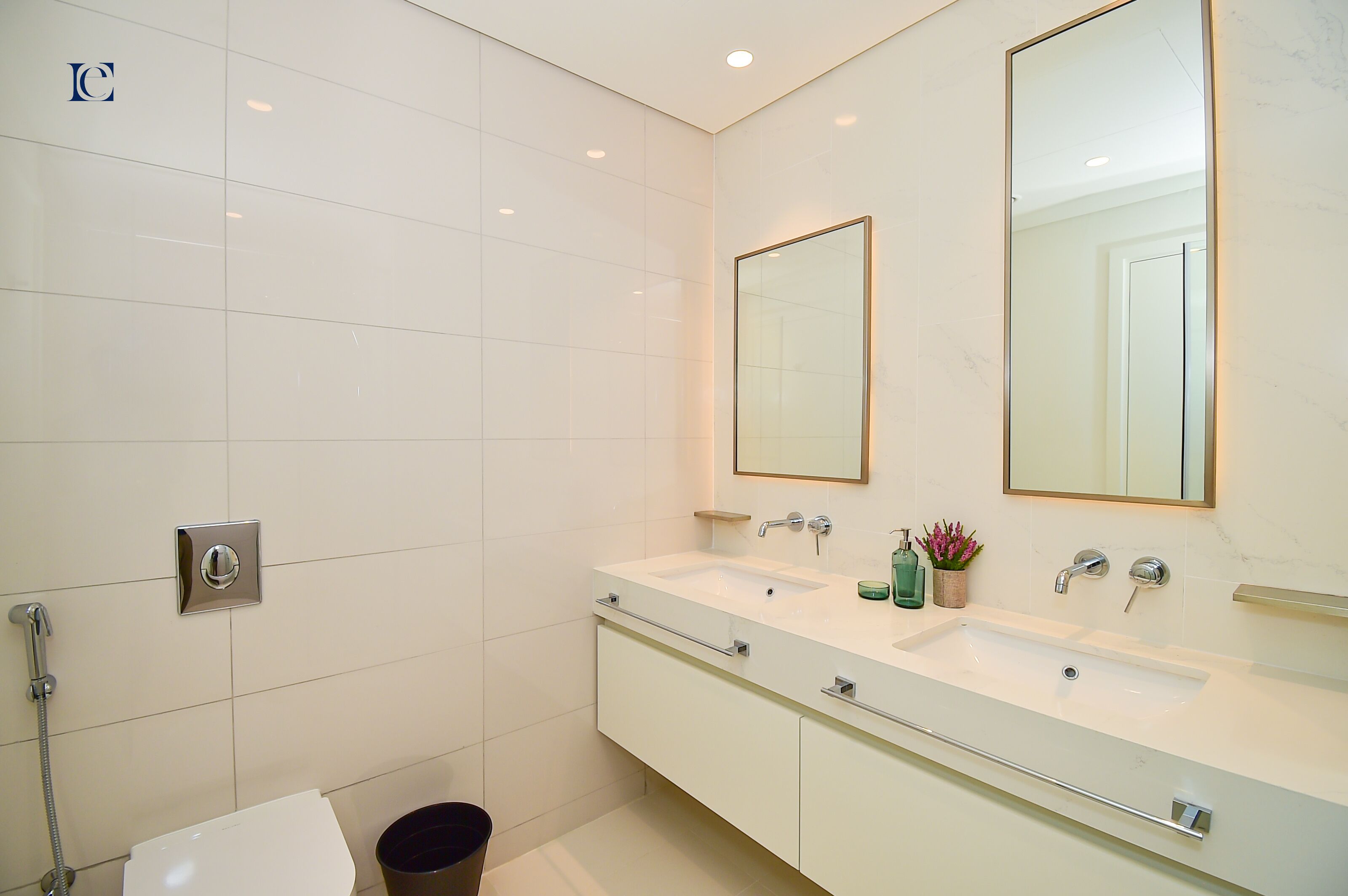 Une salle de bain moderne avec un lavabo blanc, deux miroirs et une douche.