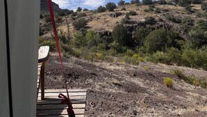 Vista desde el interior de un vehículo, mostrando un paisaje montañoso y seco con vegetación escasa bajo un cielo azul despejado.