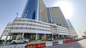 Un edifici modern amb façana corbada, diversos balcons i una prominent torre cilíndrica.