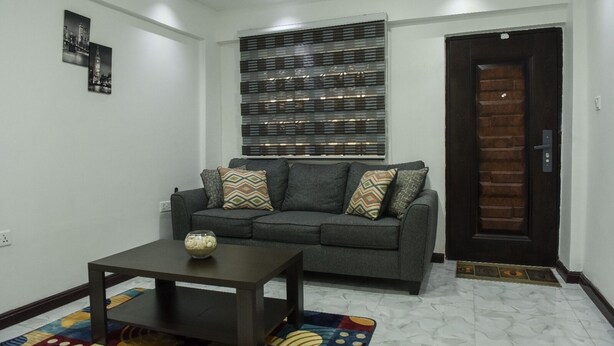 A living room with a grey sofa, patterned cushions, a coffee table, and a decorative wall piece. - 1 Bed Apartment Sleeps 2 -free Parking - Tv & Wifi (Santeo)