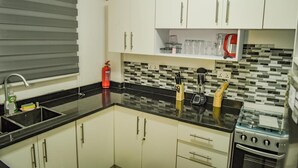 A compact kitchen with white cabinets, a black countertop, and a stove. - 1 Bed Apartment Sleeps 2 -free Parking - Tv & Wifi (Santeo)