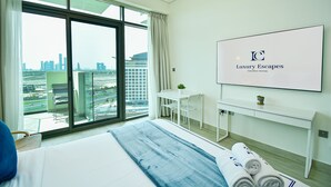 Habitación de hotel con un ventanal grande, una cama, un escritorio y un televisor mostrando 'Luxury Escapes Vacation Homes'.