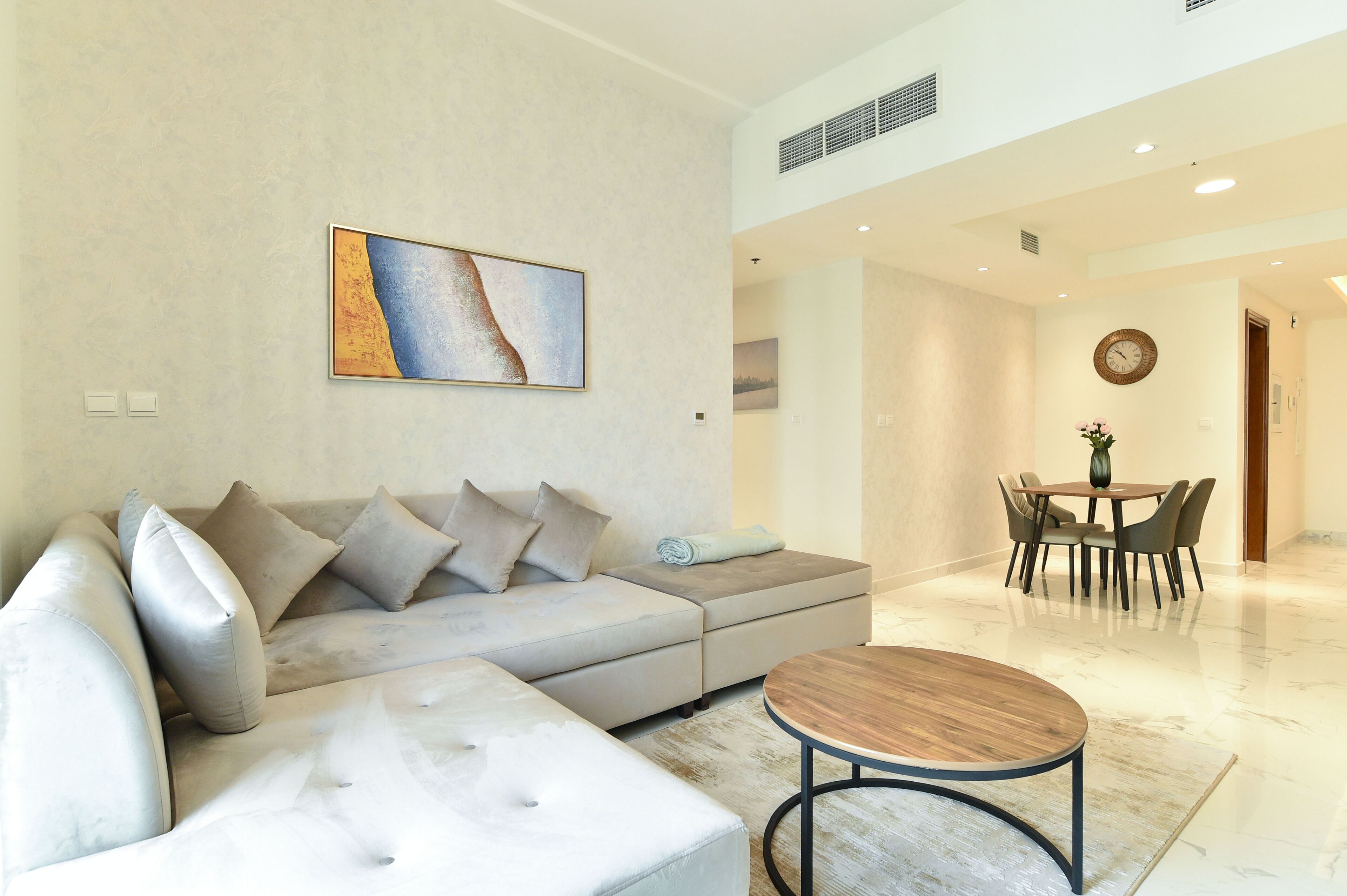 Una sala de estar moderna con un sofá modular, una mesa de centro redonda y un comedor con mesa y sillas.