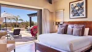 A bedroom with a large bed, a chair, a table, and a view of the outdoors. - 5-BR Luxury Golf Villa Retreat (Cabo San Lucas)