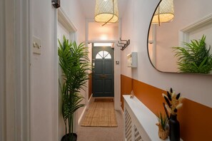 A hallway with a door, a mirror, and a plant. - Joseph Suite by Koya Homes (Vale of Glamorgan)