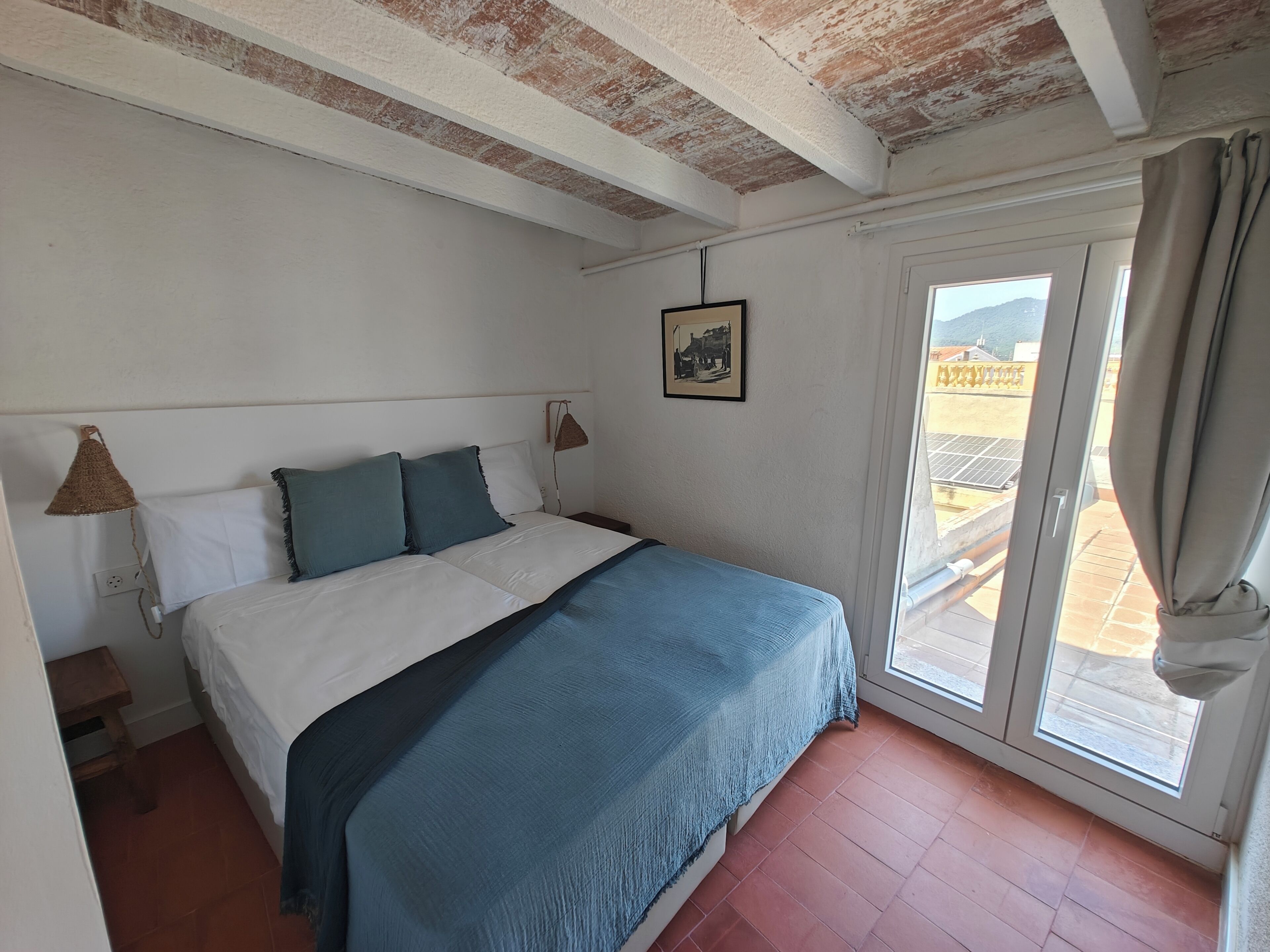 A bedroom with a bed, a window, and a picture on the wall.