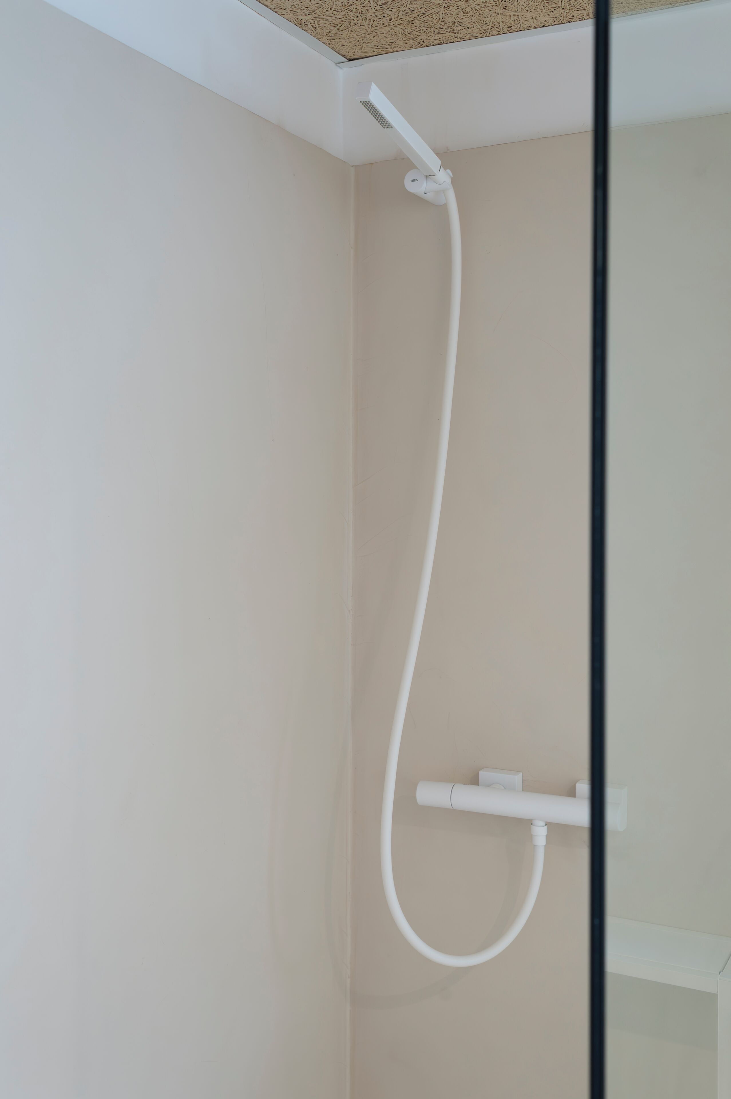 A shower with a hose and control panel, mounted on a plain wall.