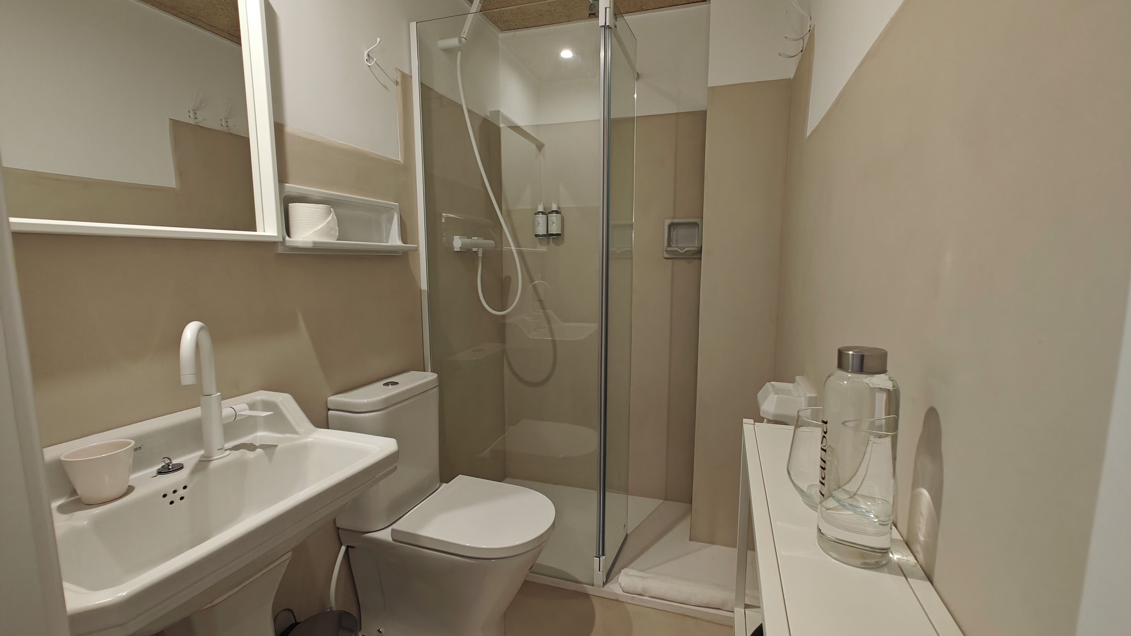 A modern bathroom with a glass-enclosed shower, a white sink, and a toilet.