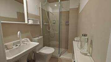 A modern bathroom with a glass-enclosed shower, a white sink, and a toilet.